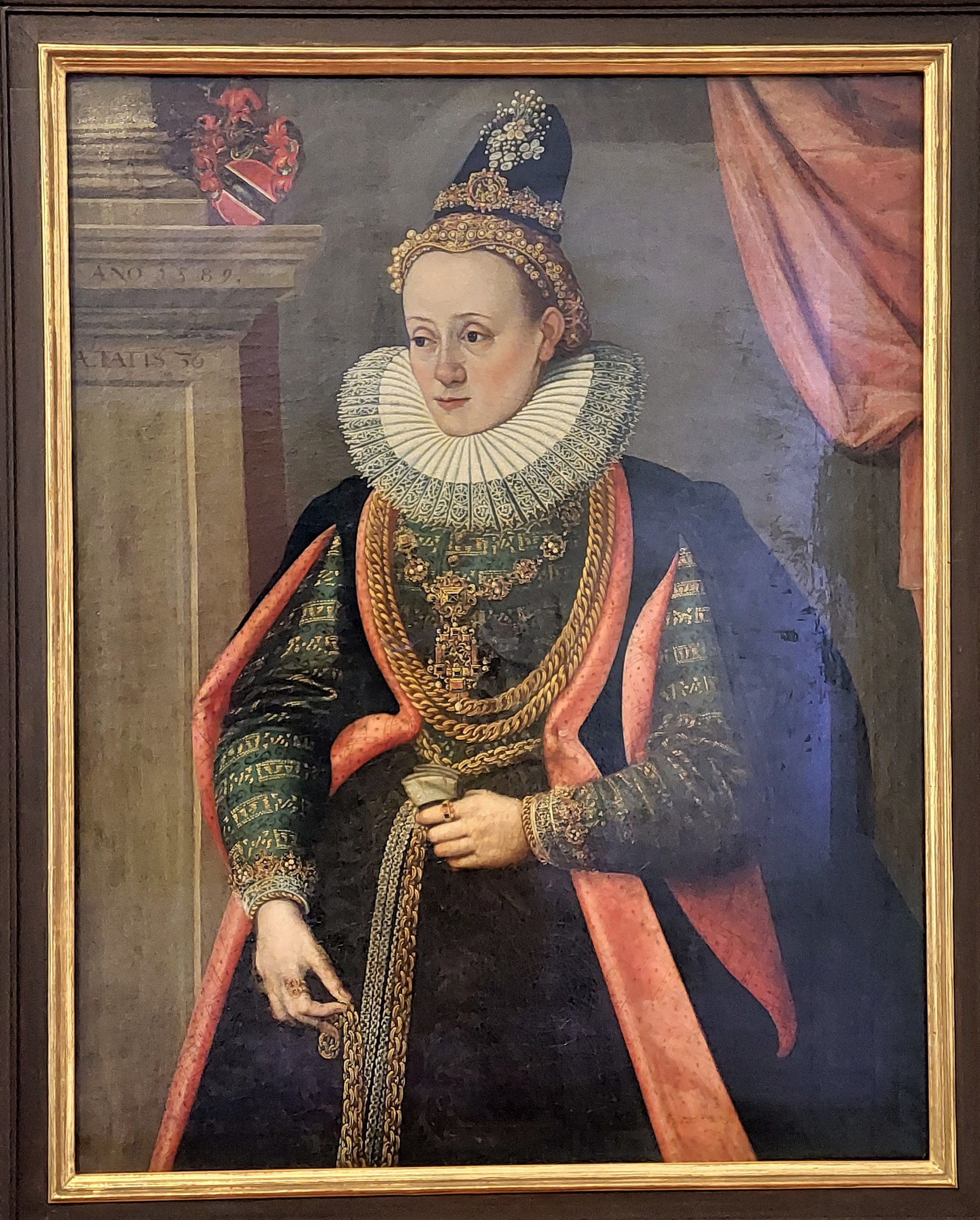 Porträt der Queen Elizabeth I. von England in königlicher Kleidung mit einer Krone und Tiara, ihr Haar ist zu einem Dutt gebunden, sie schaut zur Seite mit einem würdevollen Ausdruck, dargestellt in einem Rahmen auf einer Wand.