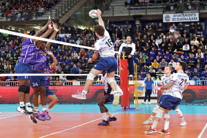 Eine Gruppe von Männern, die Volleyball auf einem Court mit einem Netz spielen, mit Zuschauern im Hintergrund und Bannern, die auf ein Futsal-Weltmeisterschaftsfinale hinweisen.