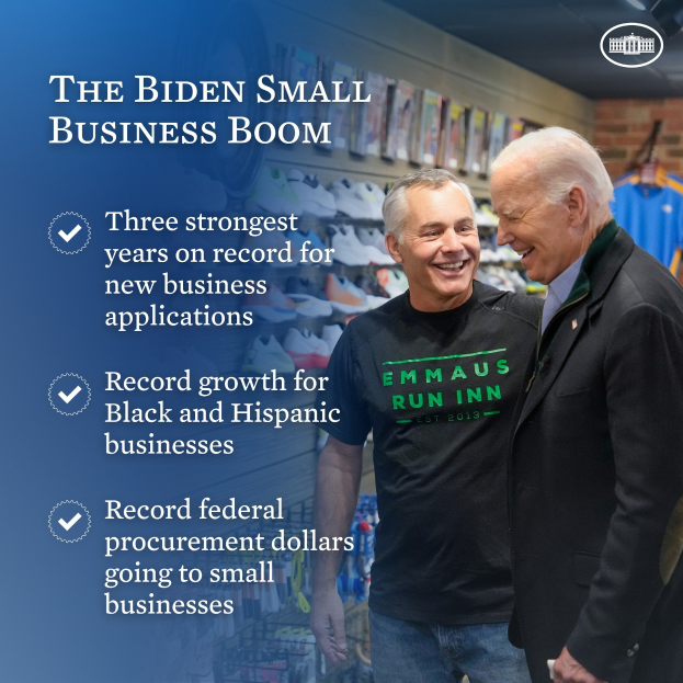 Zwei Männer, die lächeln und einer hält ein Objekt, mit dem Text "The Biden Small Business Boom" auf der linken Seite und Kleidung im Hintergrund.