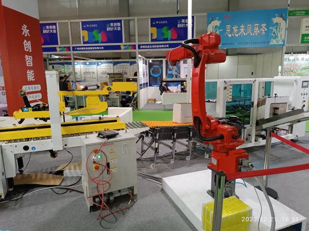 Eine Gruppe von Robotern auf einem Tisch in einer Fabrikumgebung umgeben von Maschinen, Kabeln, Platinen und Menschen im Hintergrund.