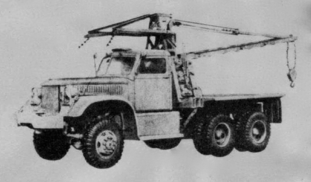 Ein Schwarz-Weiß-Foto eines großen, vierrädrigen Trucks mit einem Kran auf der Rückseite und einem Flachbettanhänger.