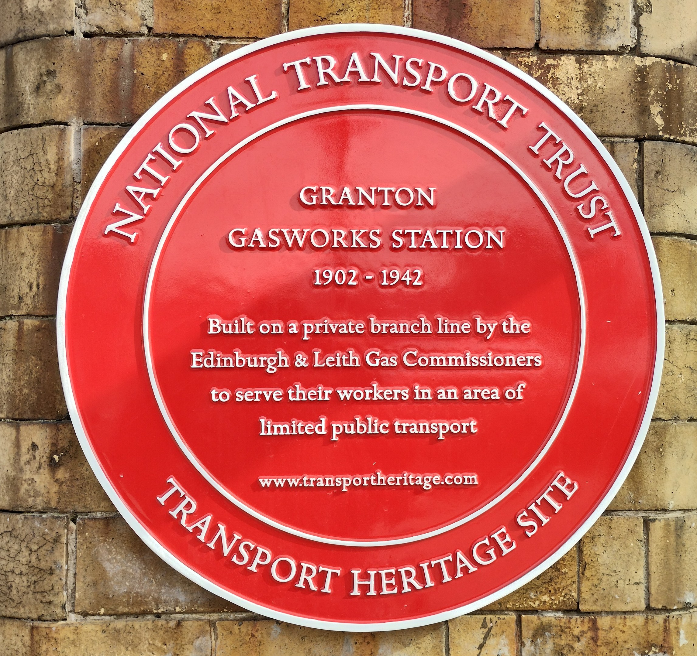 Runder roter Schild an einem Backsteingebäude mit "National Transport Trust"-Text.