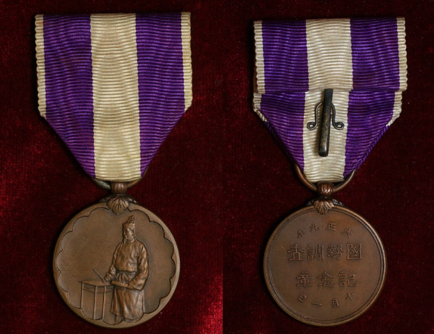 Zwei Medaillen mit lila und weißen Bändern, beschriftet, auf einer maronenfarbenen Oberfläche.