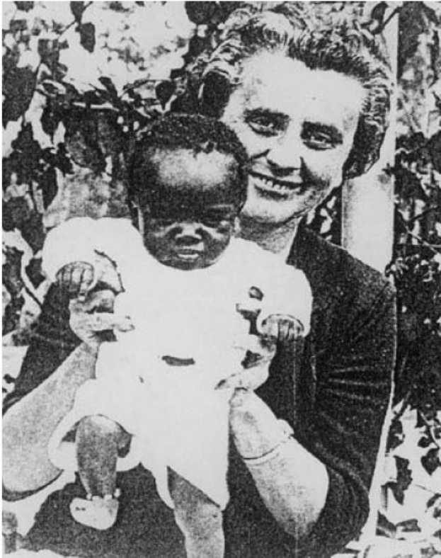 Ein Schwarz-Weiß-Foto einer Frau, die strahlend ihr Baby hält, mit Blättern im Hintergrund.